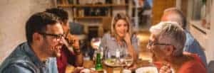 Zu sehen sind 5 glückliche Erwachsene beim Abendbrot mit Wein und Bier