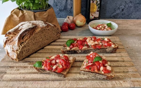 Bruschetta mit Roggenbrot, Zwiebeln, Tomaten, Knoblauch und Basilikum